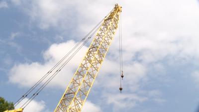 A large yellow crane located on US 13 Business in Salisbury over the Wicomico River stands stationary against a blue sky with some clouds. 