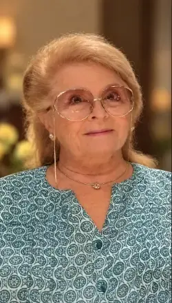 women with blond short hair, wearing glasses and green paisley, button down front top