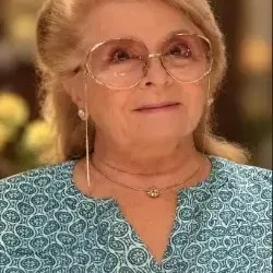 women with blond short hair, wearing glasses and green paisley, button down front top