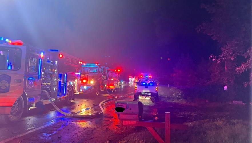 Emergency vehicles line up along a roadway during a crash and car fire response.