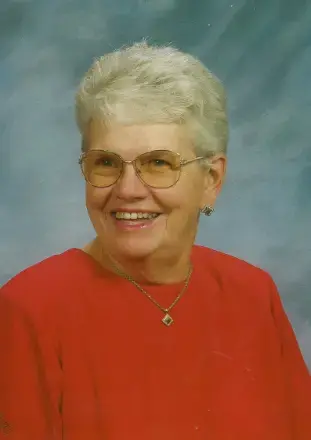 woman with grey hair wearing glasses, a red top and necklace