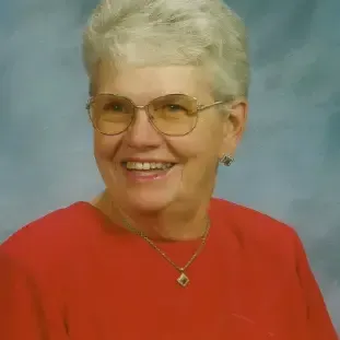 woman with grey hair wearing glasses, a red top and necklace