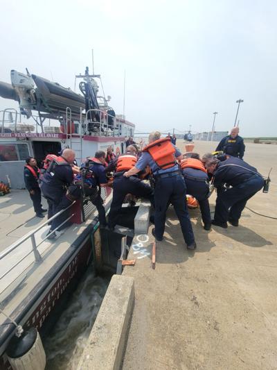 Crews work to transfer a man from a fireboat to an ambulance at the Port of Wilmington on May 23, 2023