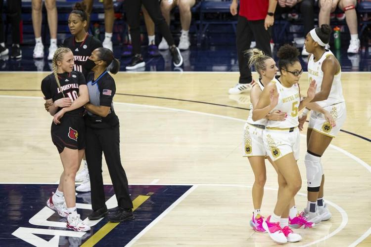 An official holds Louisville's Hailey Van Lith while Notre Dame's Dara Mabrey holds teammate Olivia Miles.jpeg