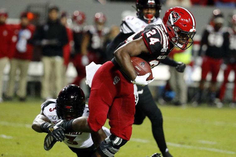 North Carolina State's Zonovan Knight (24) tries to break the tackle of Louisville's Russ Yeast