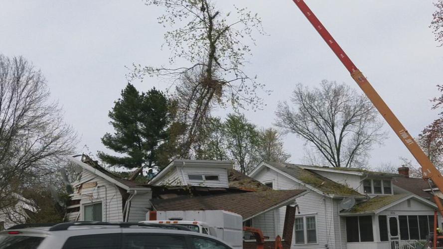 Crews work to remove tree that split a house in half during Wednesday's storms.