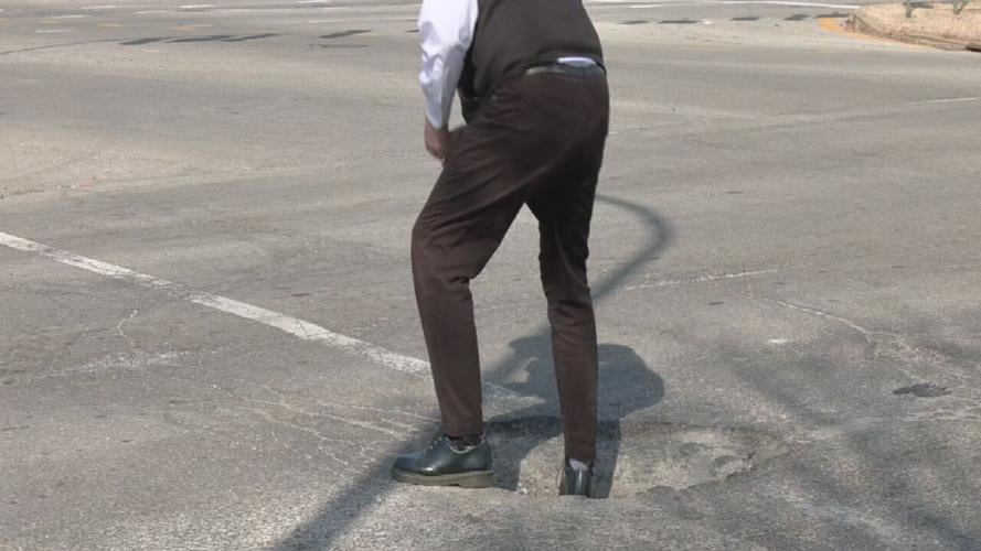 Richard Essex measures the depth of a pothole