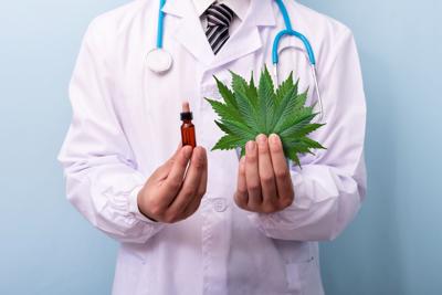 Doctor hands holding cannabis leaves and oil. Doctor prescribing marijuana extract.