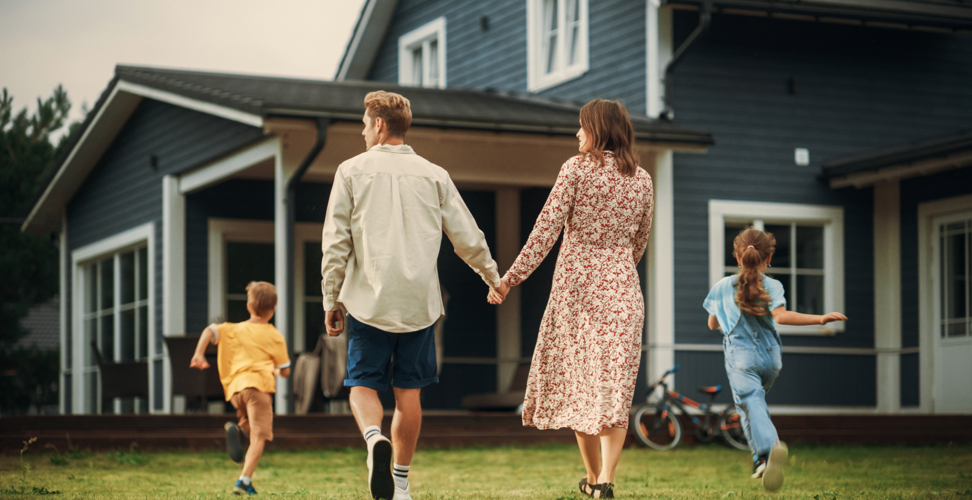 Familly holding hands and walking towards a house.