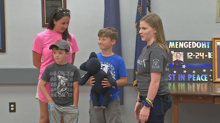 Megan O'Grady presents Blue Line Bear to Preston, the son of fallen LMPD Det. Deidre Mengedoht
