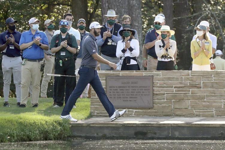 Dustin Johnson walks over the Sarazen Bridge on his way to the 15th green as spectators applaud during the final round of the Masters golf tournament