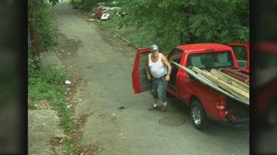 Man illegally dumping garbage into an alley in District 6