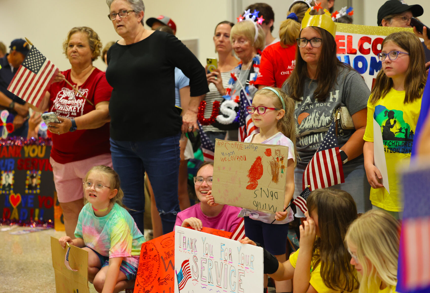 Young girls hold up signs at Honor Flight Return Home.JPG