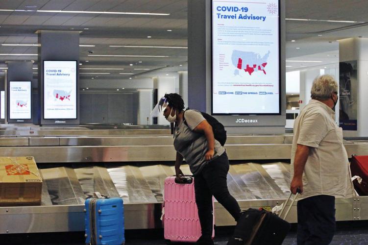 Traveler wearing PPE picks up luggage at LaGuardia Airport