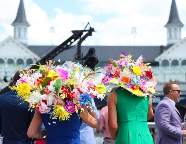 Two women with fish bowl hats stand by spires.JPG
