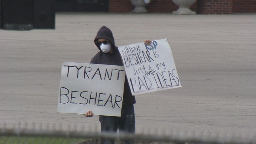 Man holds signs protesting Beshear outside of Maryville Baptist Church