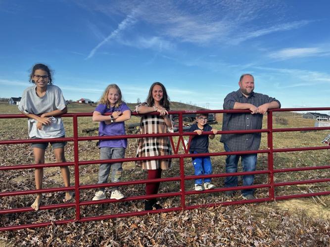 Wooldridge family smiles alongside gate by their new home