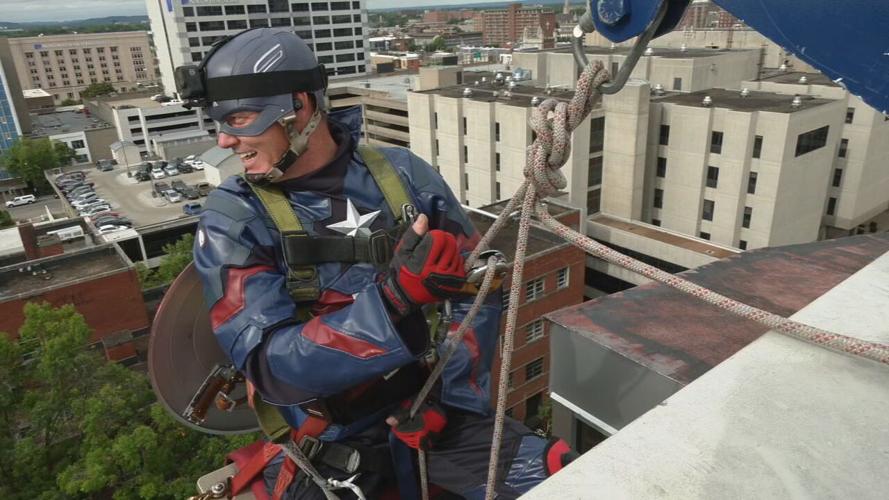 A window washer rappels from the side of Norton Children's Hospital dressed as Captain America