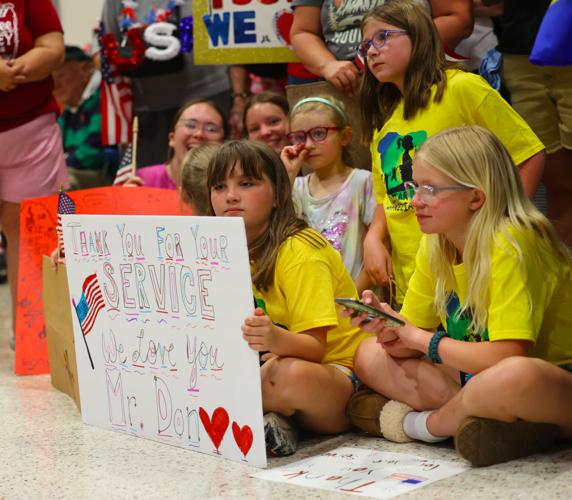 Girls hold up signs for veterans at Honor Flight.JPG