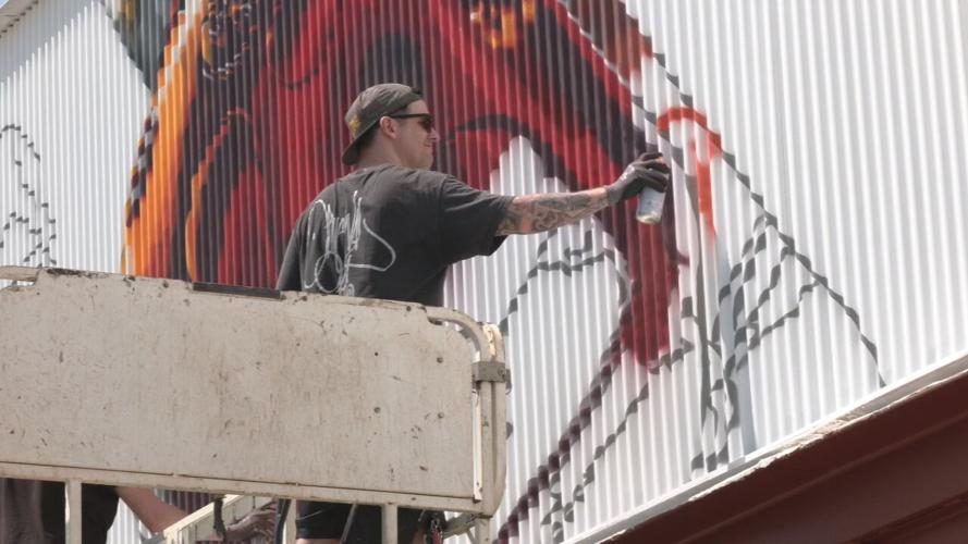 Artist works on a Derby mural in Louisville's Paristown arts district