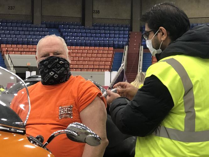 Volunteer administers COVID-19 vaccine in Broadbent Arena