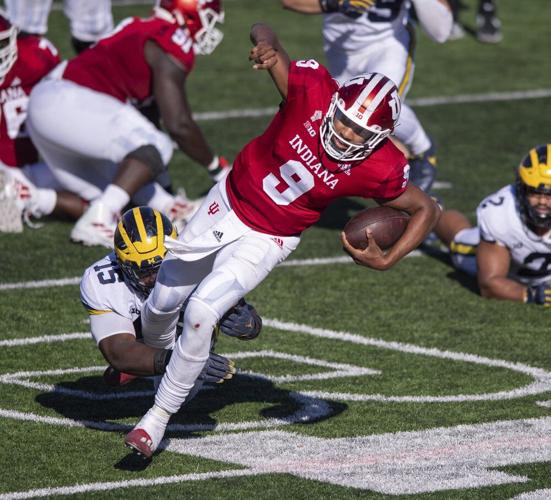 Indiana quarterback Michael Penix Jr. (9) is tripped up by Michigan defensive lineman