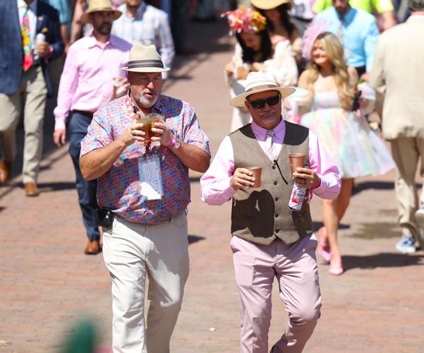 Men walk with drinks at race.JPG