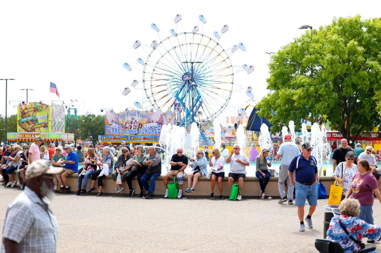 People wait at fountain with rides behind.JPG