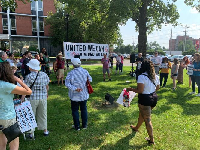 People hold signs at JCPS meeting