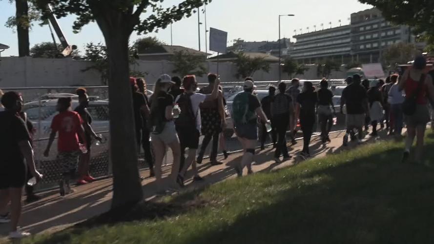 Protesters march by Churchill Downs during Derby day