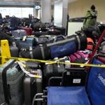A worker pauses while sorting through a pile of unclaimed luggage.jpg