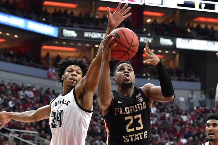 Florida State guard M.J. Walker (23) attempts to shoot past the defense of Louisville forward Dwayne Sutton