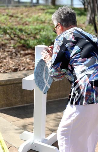 Woman writes on cross at vigil.JPG