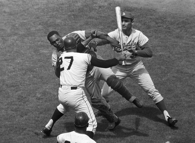 San Francisco Giants pitcher Juan Marichal (27) swings a bat at Los Angeles Dodgers catcher John Roseboro
