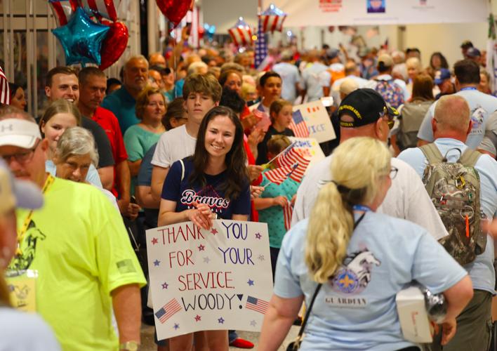 Woman holds Thank You Woody sign at Honor Flight Return Home.JPG