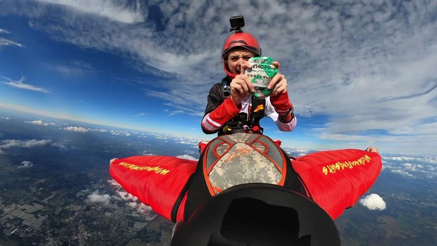 McKenna Knipe holds BK sandwich while skydiving