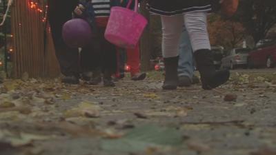 Trick-or-treaters roam sidewalk on Halloween