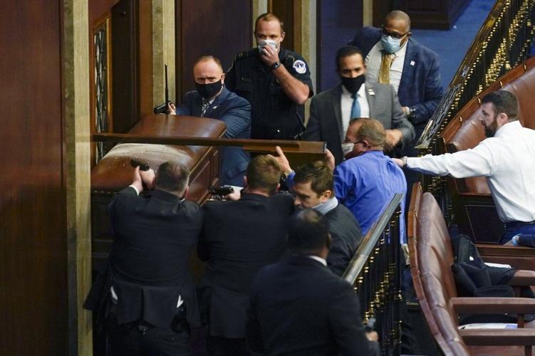 U.S. Capitol Police with guns drawn stand near a barricaded door as protesters try to break into the House Chamber