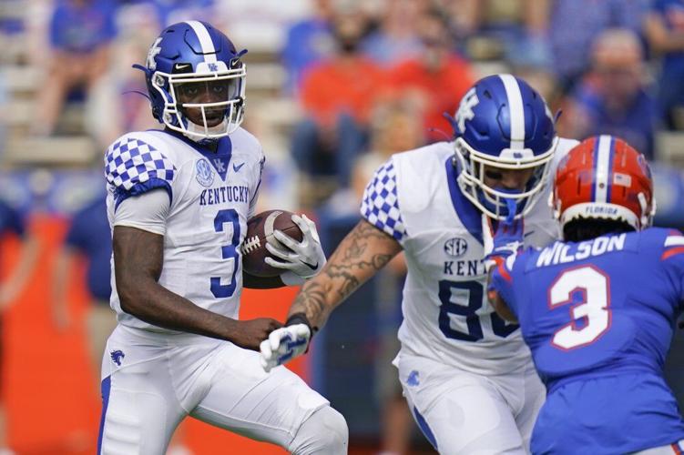 Kentucky quarterback Terry Wilson, left, looks for room to run as tight end Keaton Upshaw, center, blocks
