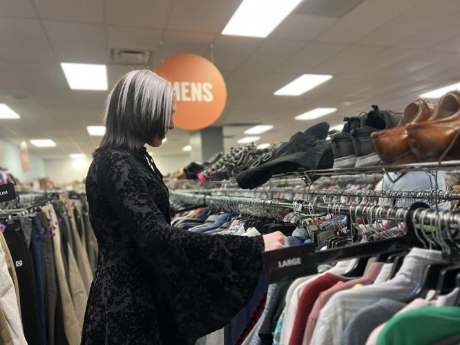 Goodwill employee rearranges clothes in aisle