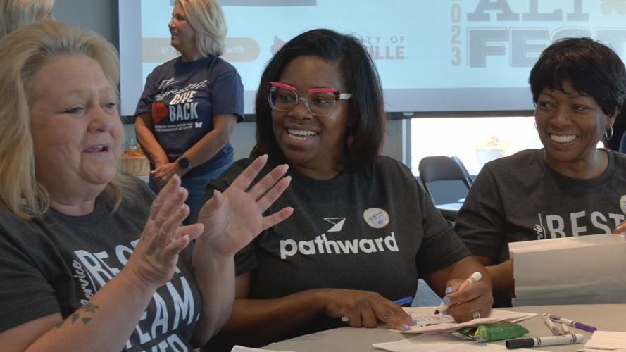 Volunteers with The Greatest Giveback chat while decorating snack bags