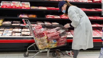Woman stocks meat case in grocery store