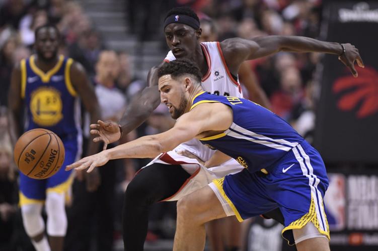 Klay Thompson and Toronto Raptors forward Pascal Siakam reach for the ball