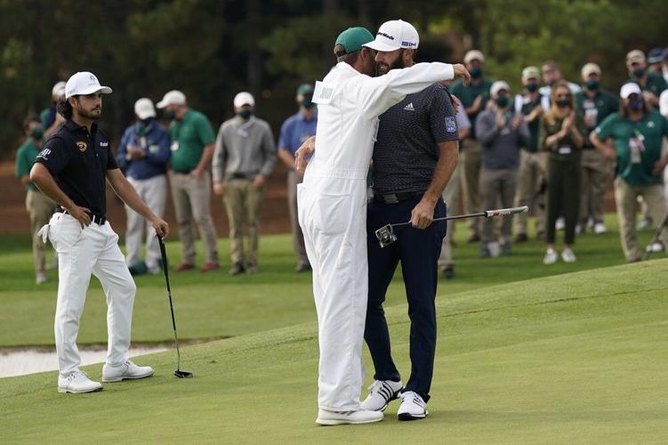 Dustin Johnson is hugged by his caddie Austin Johnson after winning the Masters golf tournament