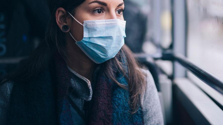 Woman wearing mask looks out window