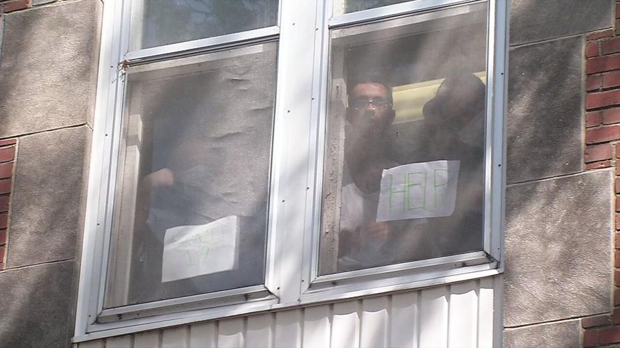 Residents of Dismass Charaties - St. Ann's halfway house hold up signs asking for help