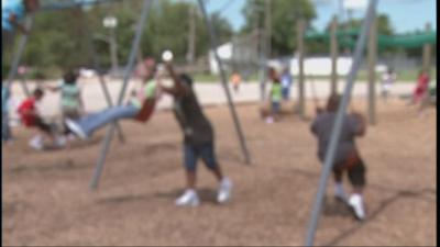 Blurred image of unidentified kids playing on swings (swingset), playground