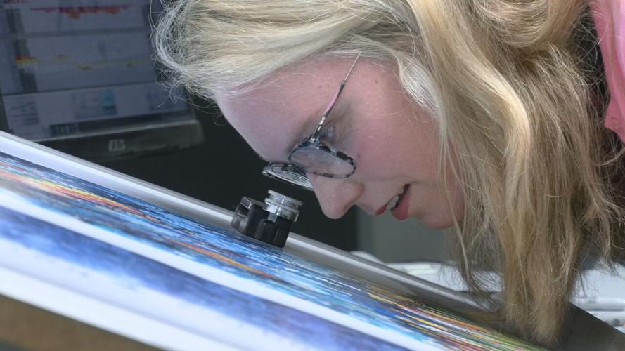 Louisville artist Liesl Long Chaintreuil examines her work, the 2023 Kentucky Derby Festival poster.