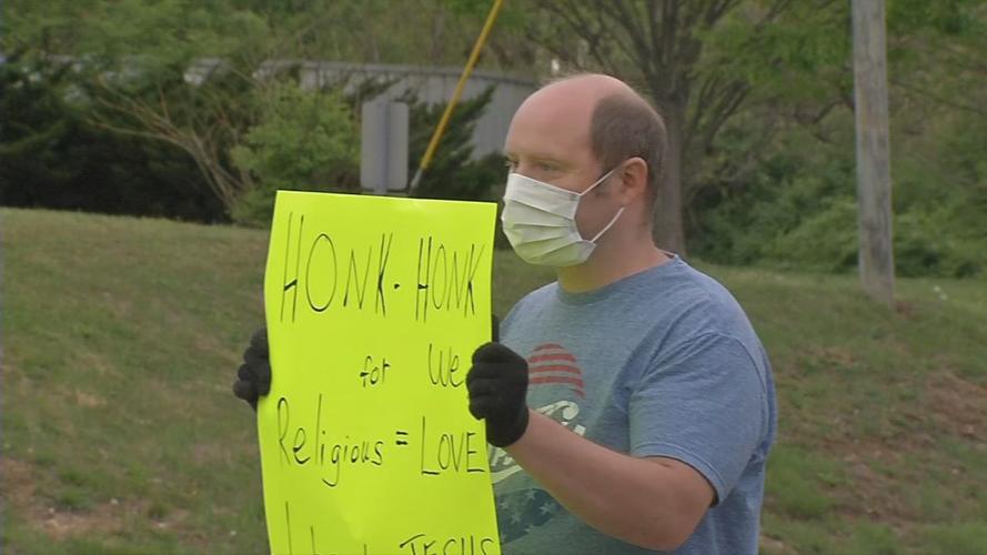 Man holds sign outside On Fire Christian Church