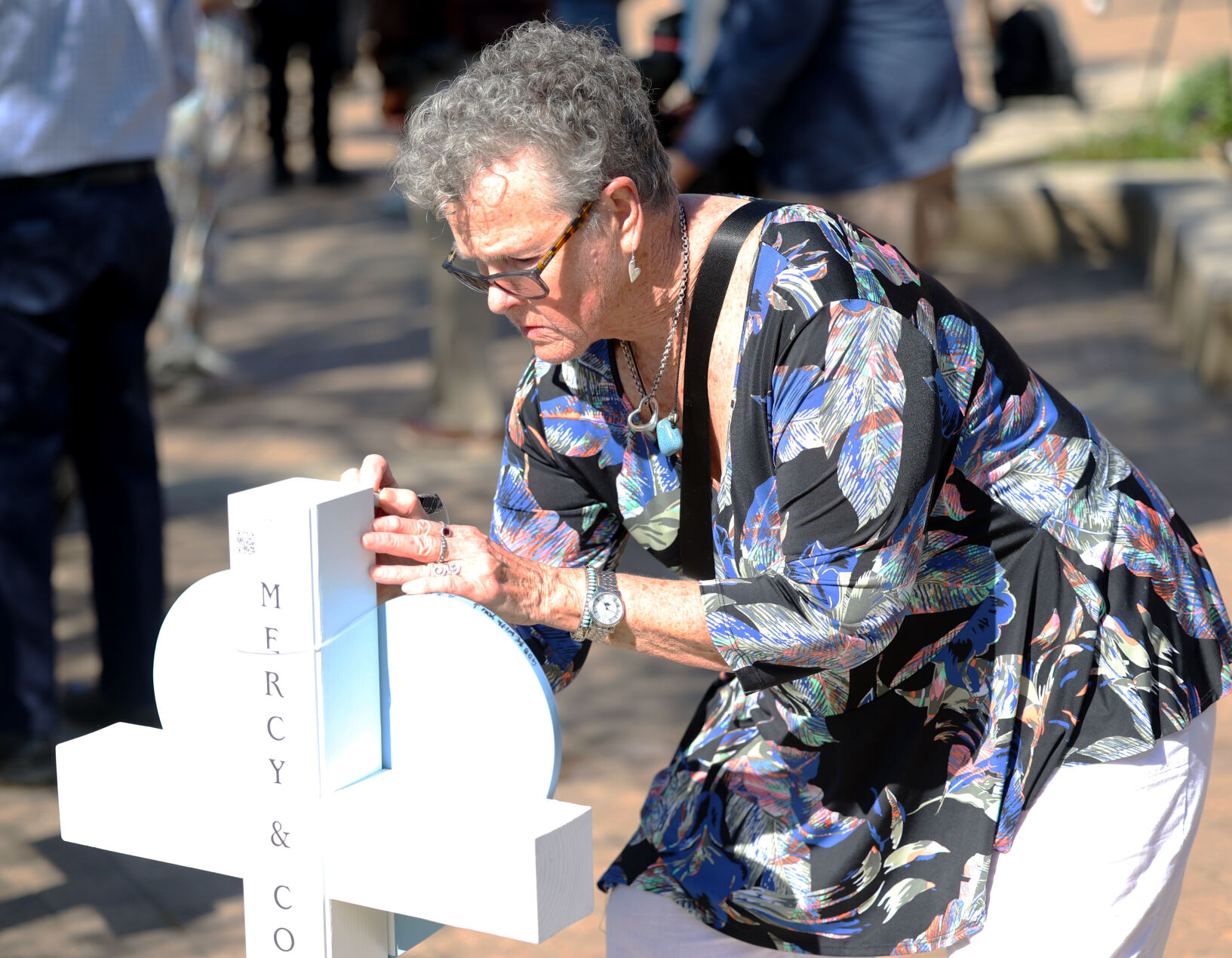 Woman writes on cross.JPG